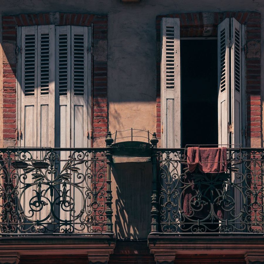Façade de maison de ville en brique et enduit, volets bois et balcons en fonte